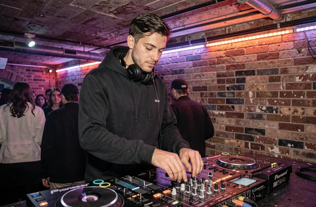 DJ Karmavibz derrière ses platines dans un club underground parisien avec une ambiance colorée